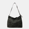 Close-up of a leopard print canvas tote bag with an adjustable strap, zipper closure, and visible interior pockets, displayed in a casual setting.