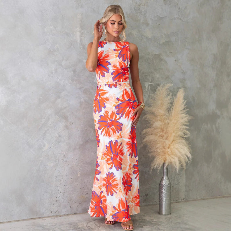 Woman modeling a one-shoulder printed sleeveless backless midi dress in lake blue, standing at sunset