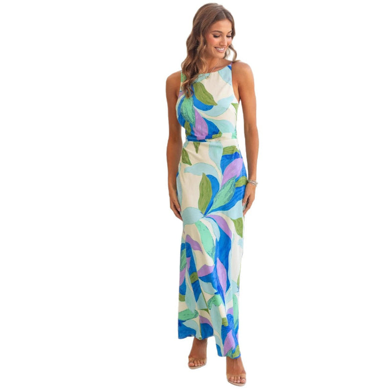 Woman modeling a one-shoulder printed sleeveless backless midi dress in lake blue, standing at sunset