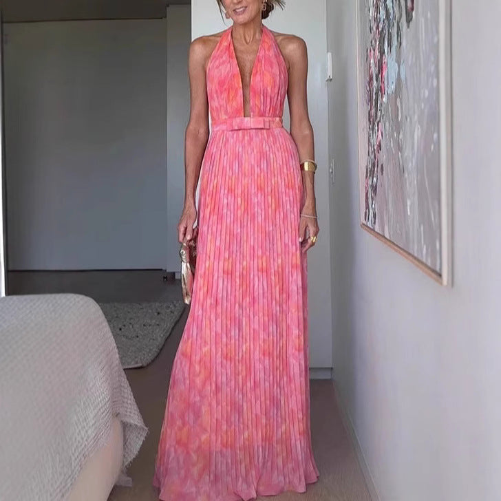 A woman from behind wearing a pink, backless, sleeveless midi dress with V-lace detailing on the back.