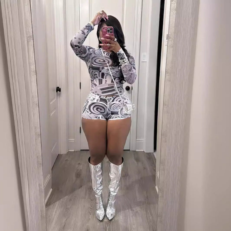 Person wearing a patterned outfit with silver high boots in a mirror selfie.