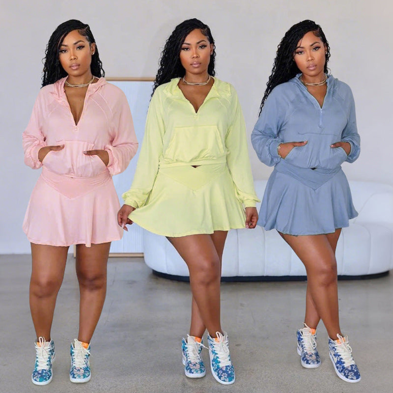 A model wearing a solid color two-piece outfit consisting of a short skirt, long pants, and a hoodie top.