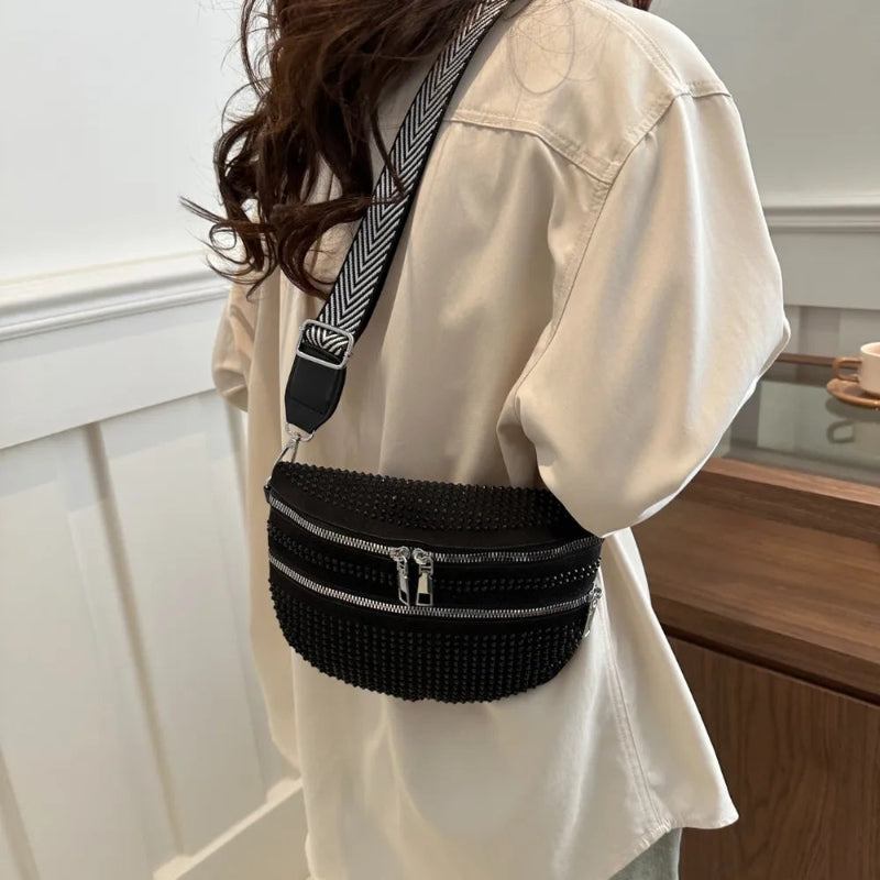 A medium-sized black crossbody bag made of PU material, adorned with metallic studs and featuring an adjustable strap.