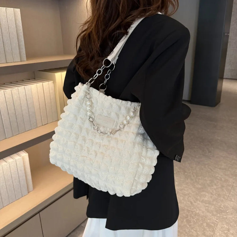 A close-up shot of a black bubble-textured tote bag with a chain detail, showcasing its unique surface and practical design.