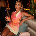 A stunning model wears a pink V-neck sleeveless halter mini dress, showcasing the stylish color-blocking pattern and fitted silhouette. The dress is perfect for a beach vacation or summer outing.