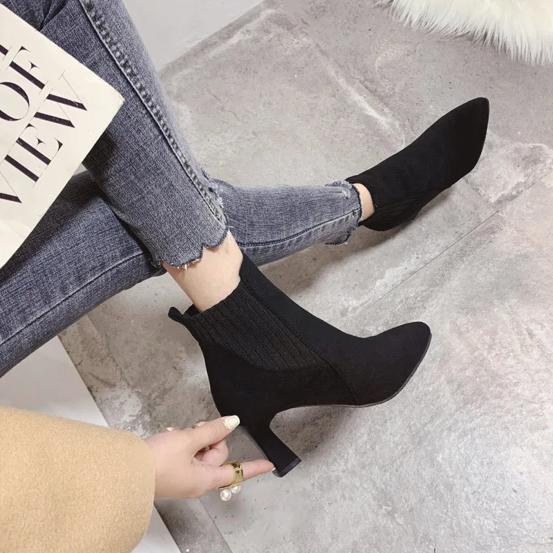 A pair of black high heel platform Martin boots with a pointed toe and thick heel.