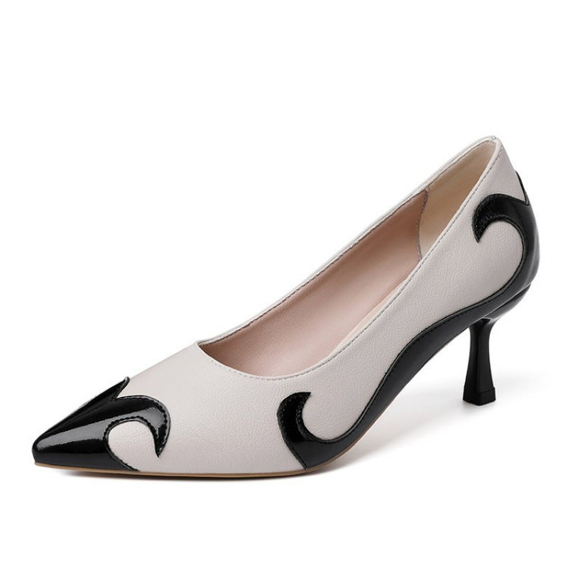 A close-up of a black satin high heel shoe with a pointed toe and a slender heel, featuring an embroidered white skull pattern and a dragonfly embellishment on the side.