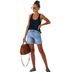 A pair of blue, high-waisted fringed denim shorts with distressed details. The shorts are laid flat on a neutral background, showcasing the style and texture. The fringe detailing is prominent along the hemline.