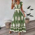 A stylish model wearing an elegant floral V-neck midi dress in a dark blue color. The dress has a waist-cinched design and a beautiful positional flower pattern, perfect for an elegant commuting style.