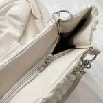 A close-up shot of a black bubble-textured tote bag with a chain detail, showcasing its unique surface and practical design.