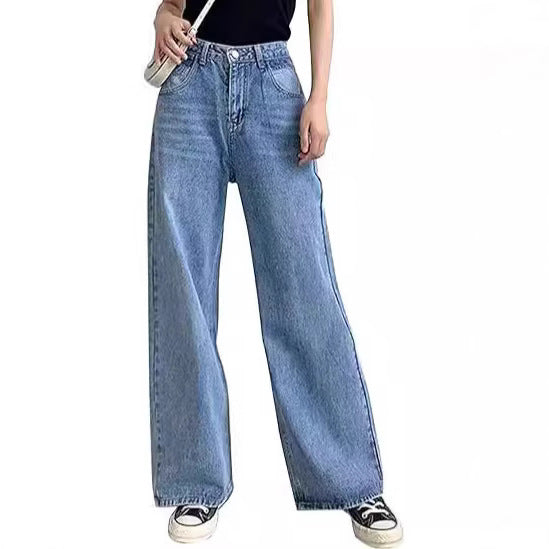 Woman wearing slim high-waisted light blue non-stretch denim jeans with a tucked-in blouse in a cityscape.