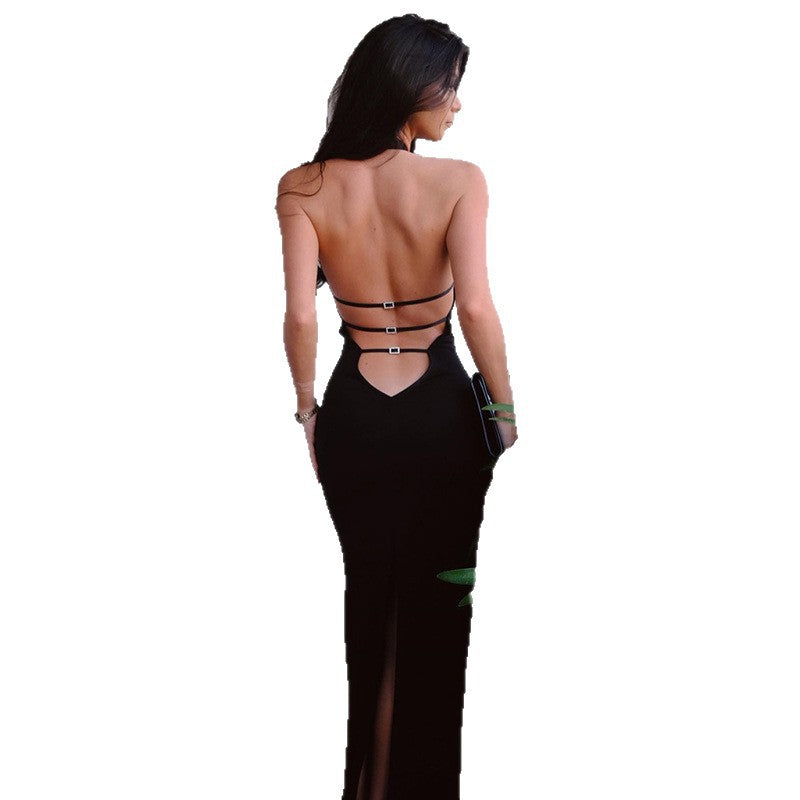 A black, sleeveless, fitted midi dress with a halter neck, a backless design, and a high slit on the side. The dress is shown hanging, highlighting its form-fitting silhouette.