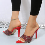 A close-up of a pair of sparkling sequin point toe mid-heel sandals in white, scarlet and black.