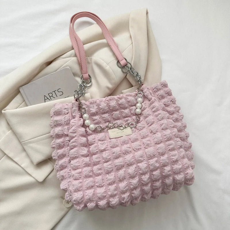 A close-up shot of a black bubble-textured tote bag with a chain detail, showcasing its unique surface and practical design.