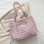 A close-up shot of a black bubble-textured tote bag with a chain detail, showcasing its unique surface and practical design.