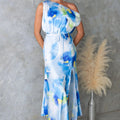 Model wearing a light blue split sleeveless printed midi dress with elegant flair in outdoor setting