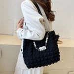 A close-up shot of a black bubble-textured tote bag with a chain detail, showcasing its unique surface and practical design.