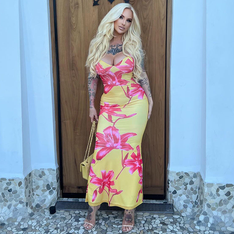 A yellow, printed strapless dress with a V-neck and a backless design. The dress is long and features a high-waist, shown laid flat to highlight the pattern and style.