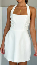 A model wearing a solid color short halter dress with a one-shoulder design.