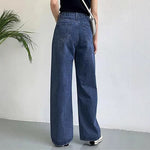 Woman wearing slim high-waisted light blue non-stretch denim jeans with a tucked-in blouse in a cityscape.