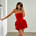 A vibrant red strapless, sleeveless mini dress with a unique one-shoulder collar and a large flower-shaped hem, made of polyester.