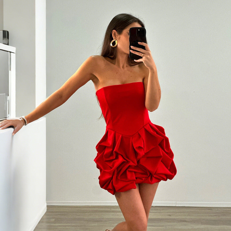 A vibrant red strapless, sleeveless mini dress with a unique one-shoulder collar and a large flower-shaped hem, made of polyester.