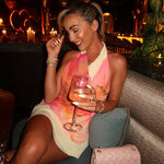 A stunning model wears a pink V-neck sleeveless halter mini dress, showcasing the stylish color-blocking pattern and fitted silhouette. The dress is perfect for a beach vacation or summer outing.