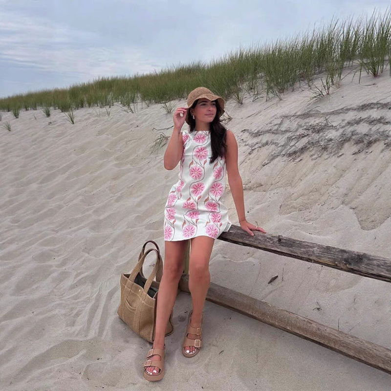 A sleeveless, short dress with a round neck, mid-waist fit, and a vibrant floral print.