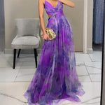 Woman wearing a strapless maxi dress with vibrant abstract print, holding gold clutch