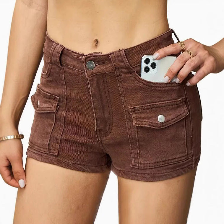 Model wearing high-waisted khaki denim shorts in street style setting, casual look with sleeveless top.
