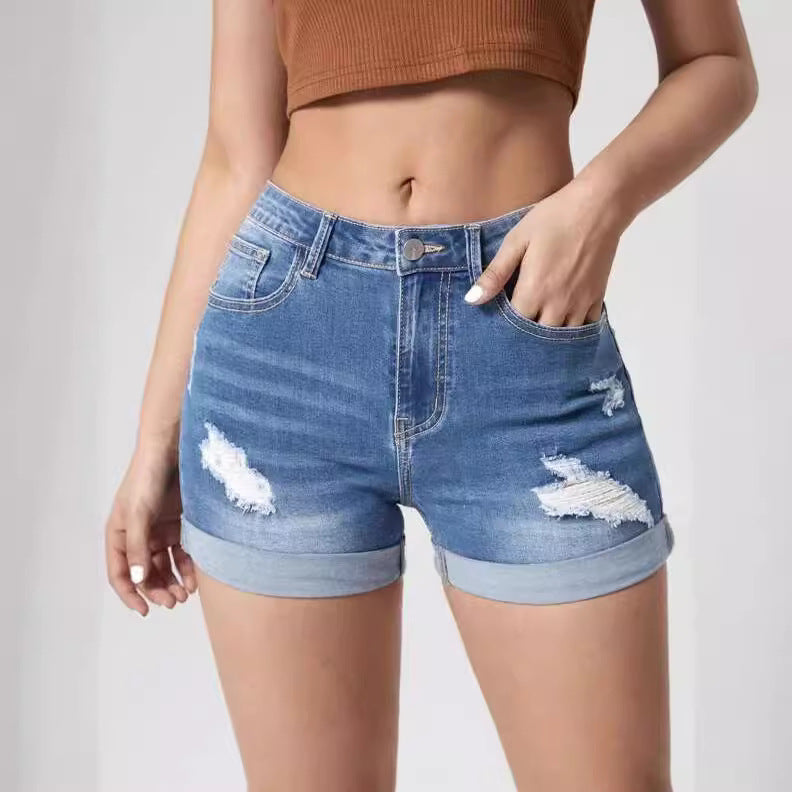 A pair of light blue, high-waisted denim shorts with distressed holes and a cuffed hem. The shorts have a skinny fit and are displayed on a flat surface.