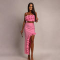 A model wearing a pink sleeveless top and a matching long skirt with a ruffle hem, part of a two-piece set.