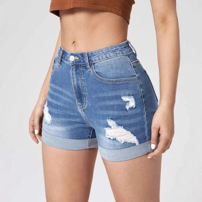 A pair of light blue, high-waisted denim shorts with distressed holes and a cuffed hem. The shorts have a skinny fit and are displayed on a flat surface.