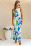 Woman modeling a one-shoulder printed sleeveless backless midi dress in lake blue, standing at sunset