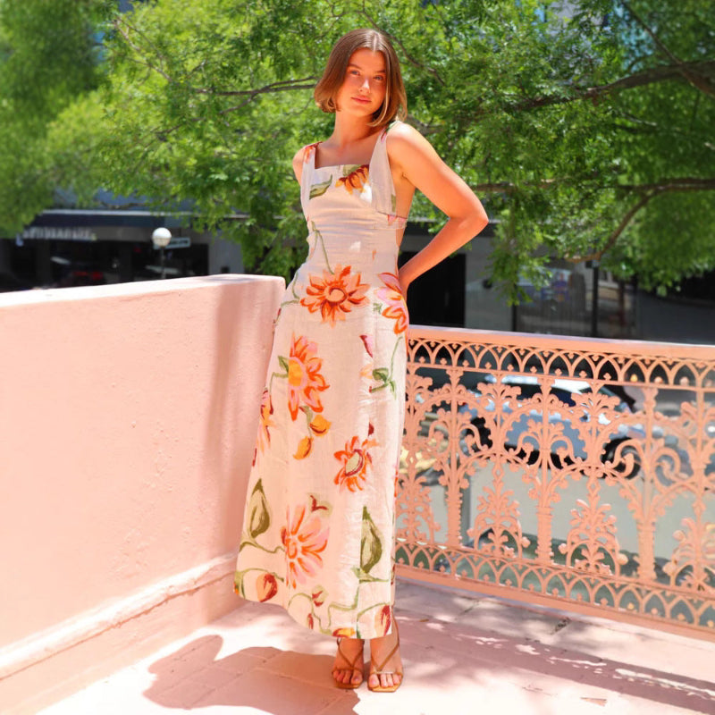 A model wearing a floral patterned, long, backless, and strapless midi dress, suitable for office wear.