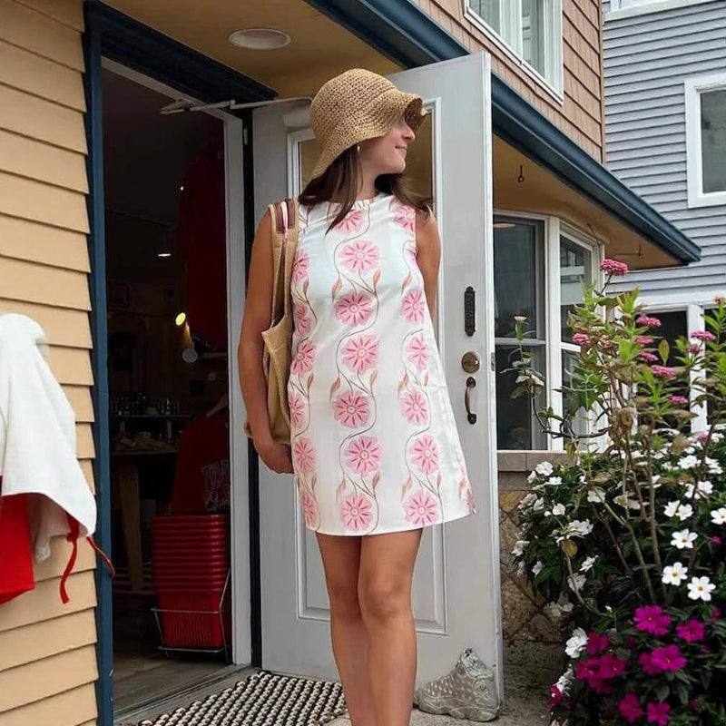 A sleeveless, short dress with a round neck, mid-waist fit, and a vibrant floral print.
