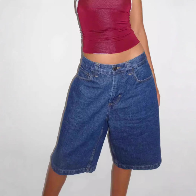 A pair of dark blue, mid-length, vintage-style denim shorts with a distressed finish. The shorts are laid flat, showcasing the straight-leg cut and medium-rise waist.