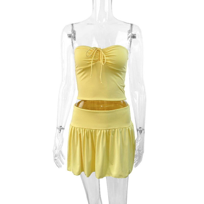 A light yellow off-shoulder tube top and a matching pleated short skirt set, displayed on a model or flat lay, showcasing a slim fit and elegant style.