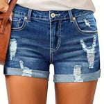 A model wearing deep blue, high-waisted denim shorts with a cuffed hem, paired with a white t-shirt. The frayed edges of the shorts are visible, and the overall style is casual and chic.