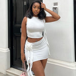  A woman wearing an embroidered flower round neck crop top and matching mini skirt set, smiling.