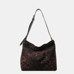 Close-up of a leopard print canvas tote bag with an adjustable strap, zipper closure, and visible interior pockets, displayed in a casual setting.