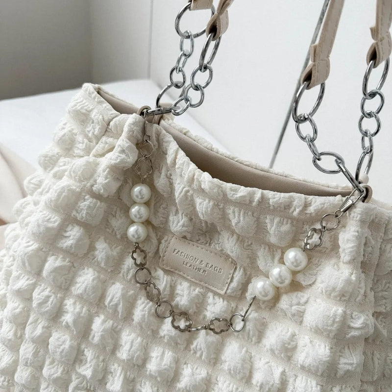 A close-up shot of a black bubble-textured tote bag with a chain detail, showcasing its unique surface and practical design.