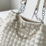 A close-up shot of a black bubble-textured tote bag with a chain detail, showcasing its unique surface and practical design.