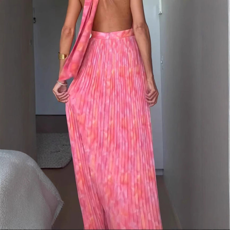 A woman from behind wearing a pink, backless, sleeveless midi dress with V-lace detailing on the back.