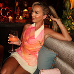 A stunning model wears a pink V-neck sleeveless halter mini dress, showcasing the stylish color-blocking pattern and fitted silhouette. The dress is perfect for a beach vacation or summer outing.