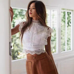 A white, sleeveless top with a semi-high collar and a delicate hollow-out geometric pattern.