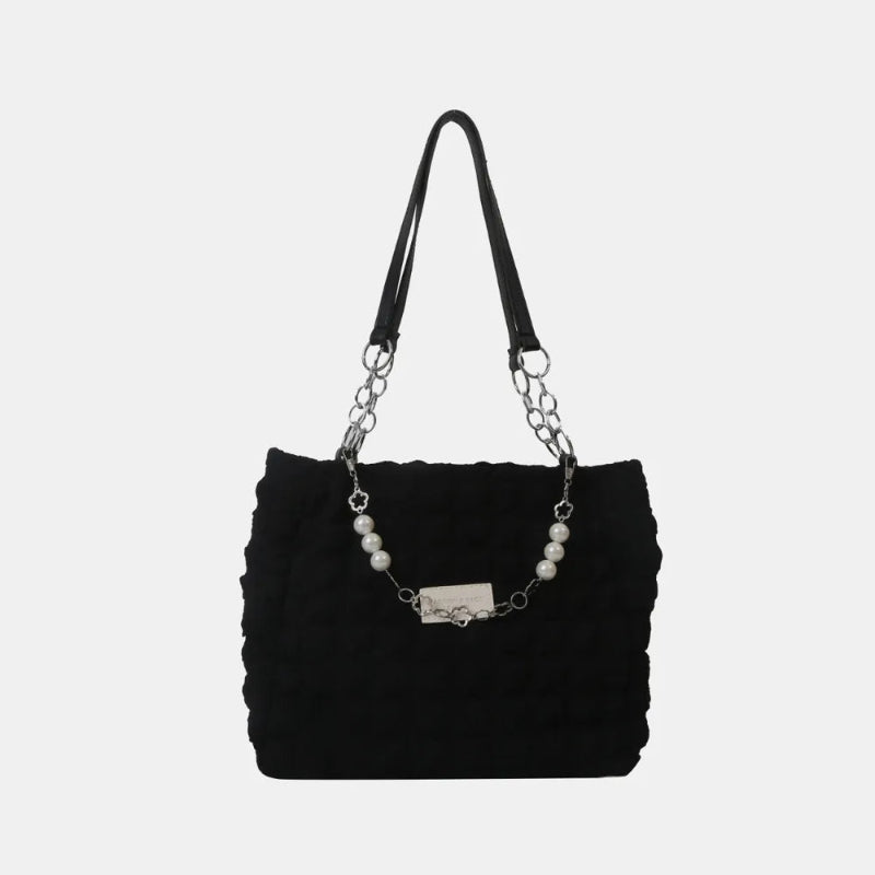 A close-up shot of a black bubble-textured tote bag with a chain detail, showcasing its unique surface and practical design.