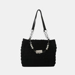 A close-up shot of a black bubble-textured tote bag with a chain detail, showcasing its unique surface and practical design.