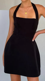 A model wearing a solid color short halter dress with a one-shoulder design.