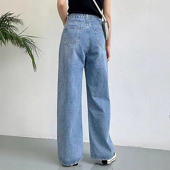 Woman wearing slim high-waisted light blue non-stretch denim jeans with a tucked-in blouse in a cityscape.